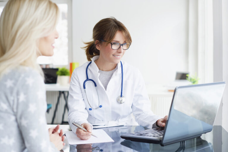 Doctor and her patient. Shot of a middle aged female doctor sitting in front of laptop and consulting with her patient